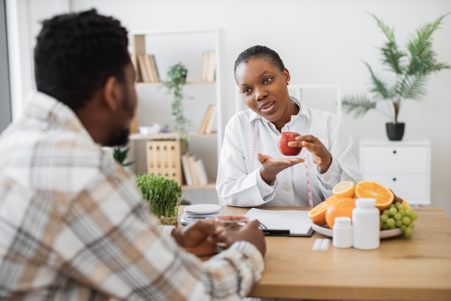 Female with apple and measuring tape talking to patient